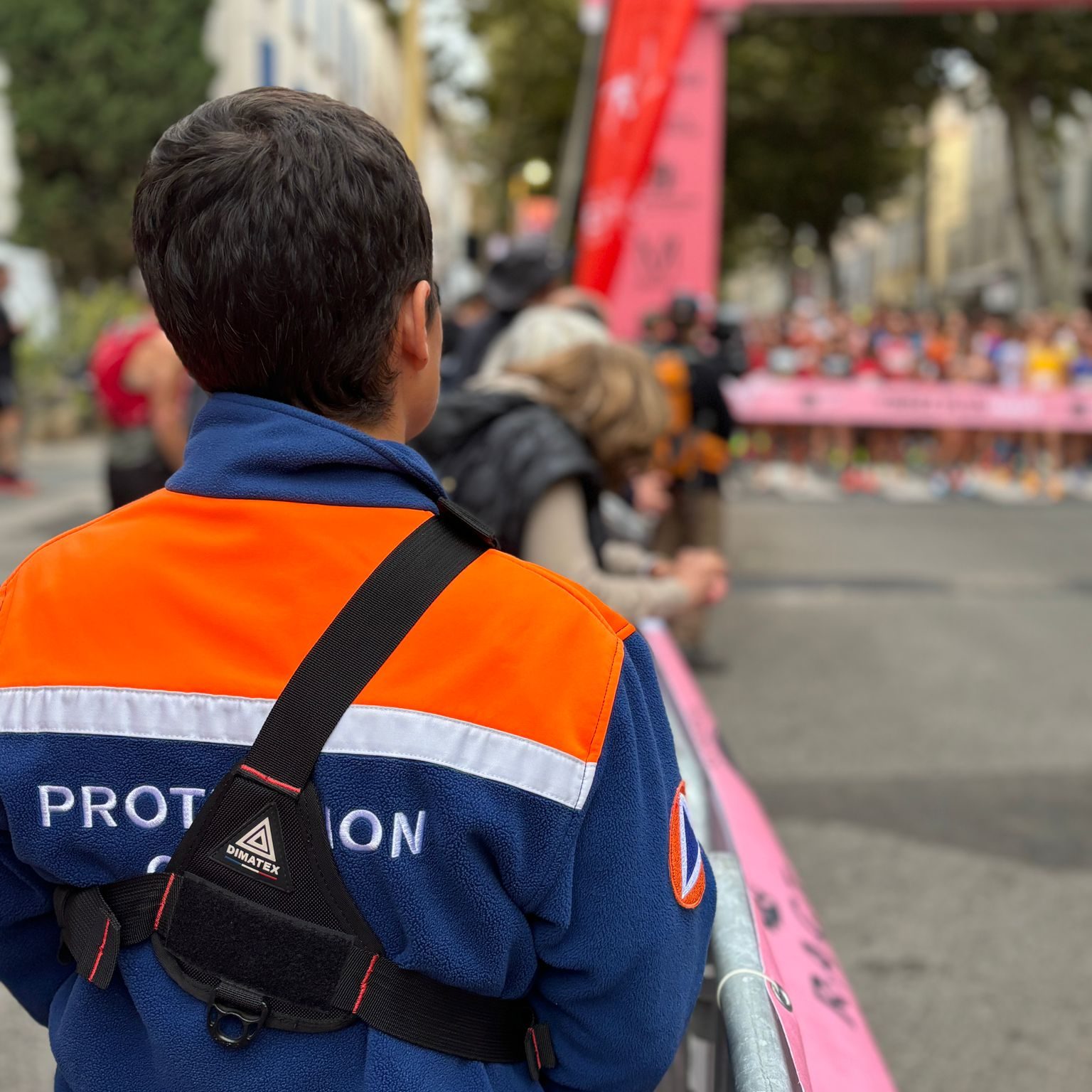 Bénéovole de dos, dans le public, face à la ligne d'arrivée.