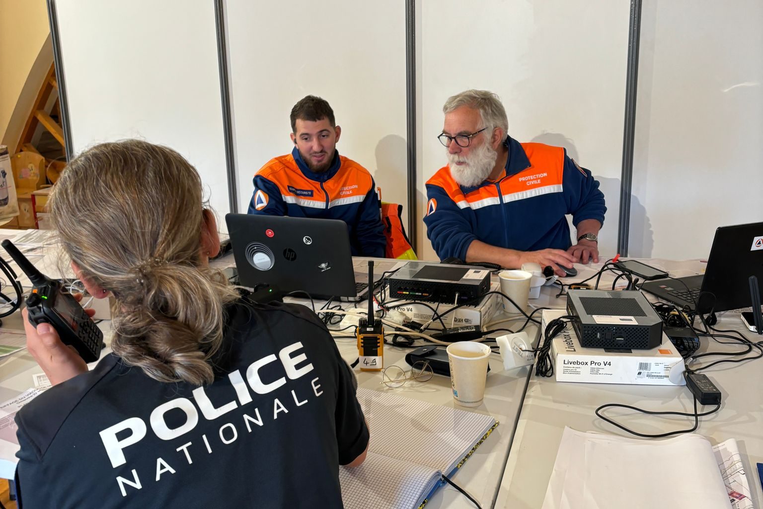 Deux bénévoles de la Protection Civile de l'Aveyron entrain de regarder un ordinateur pour surveiller la course, face à une policière.