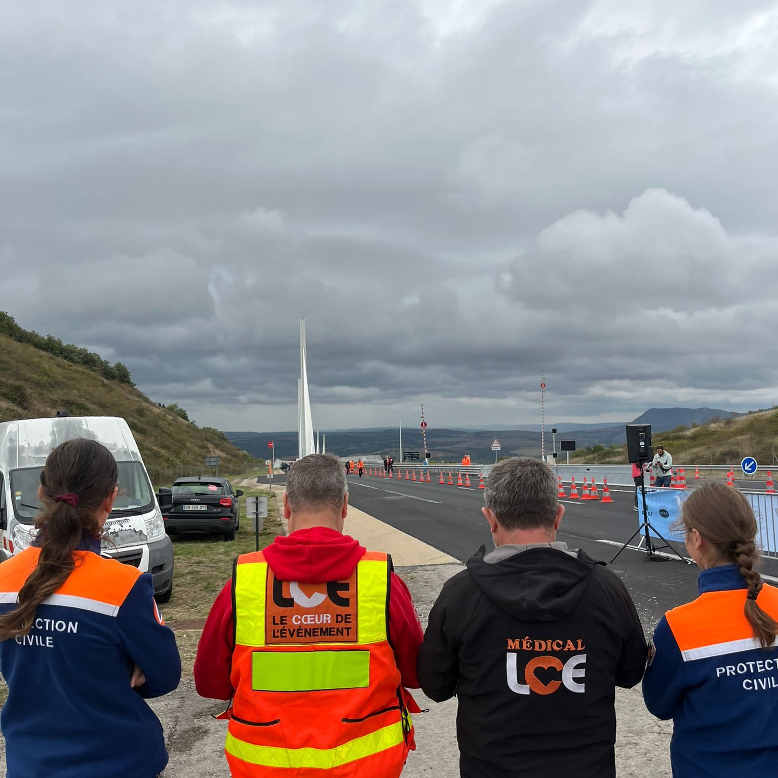 Quatre bénévoles de dos, entrain de regarder la course du Viaduc de Millau.